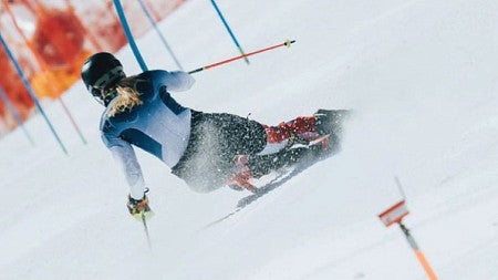 Collage of two photos of the U.S. Alpine Ski team side-by-side. First photo is of a group of three skiers in a group on the slopes facing the camera and wearing heated training shorts over the top of their regular ski outfits. Second photo is a picture of af a skier from behind as they ski down the training course for the Winter Olympics.