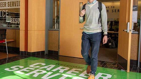 A student walks out of Mohr Career Services into the Lillis atrium